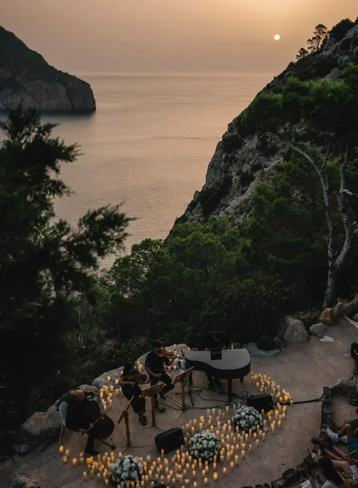 Acantilado de Ibiza al atardecer con un concierto al fondo